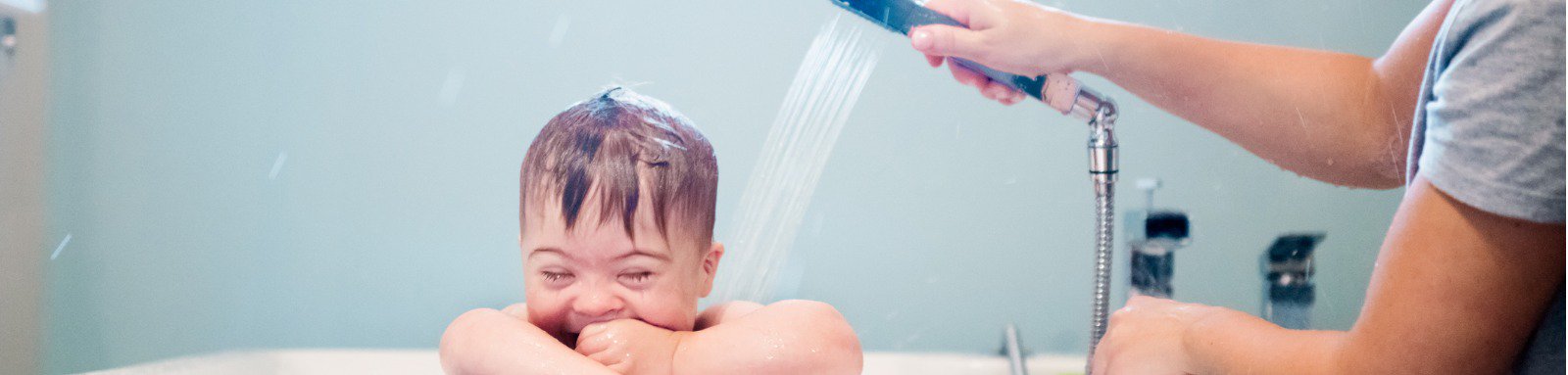 Smiling boy in bath being washed by mother
