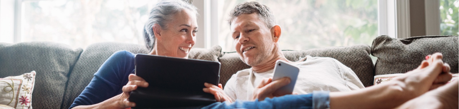 Woman and man on couch smilling and holding mobile devices