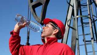 Tradesman wearing hardhat drinking bottled water