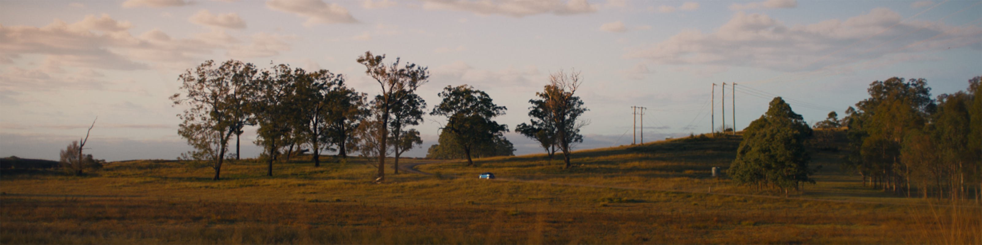 Car diving down country street in a rural Australian landscape setting 