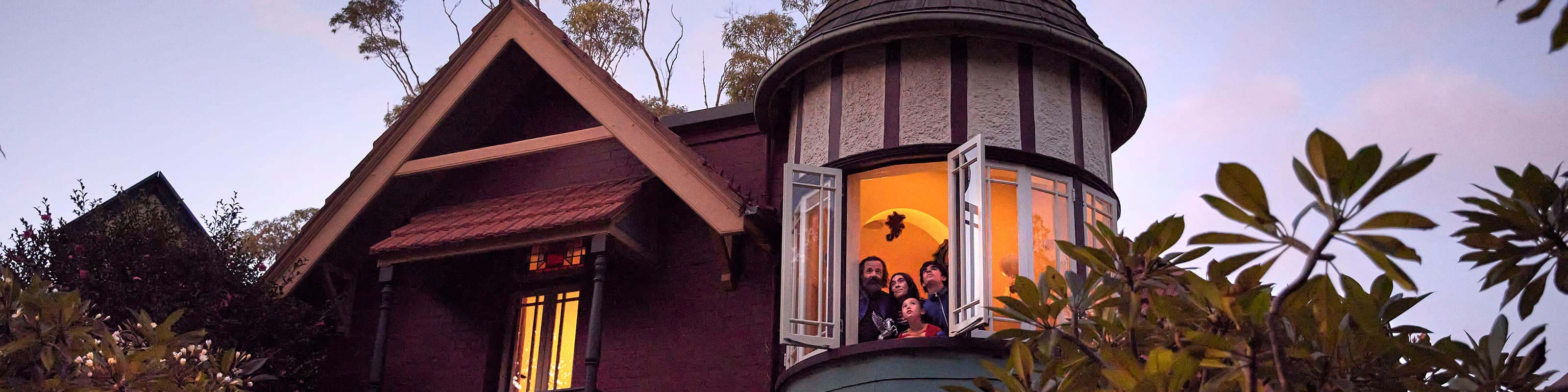 Old tudor home with family looking down from second story window
