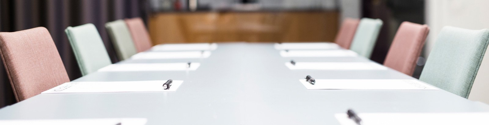 Grey boardroom table with pens and paper