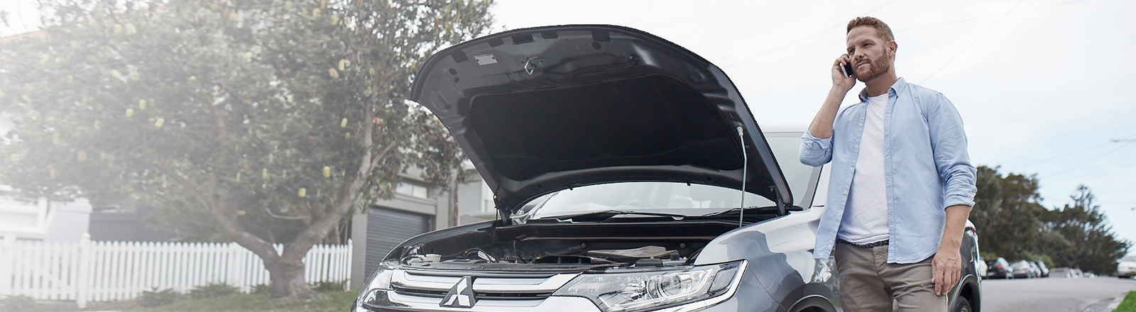Man broken down car holding a phone