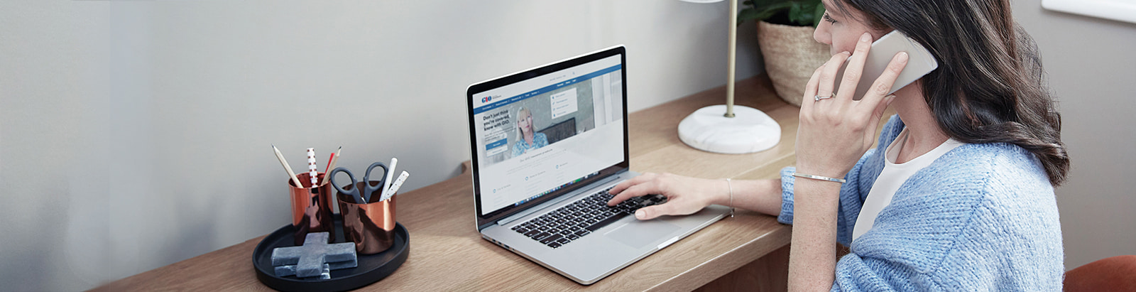 Woman talks on mobile whilst using laptop