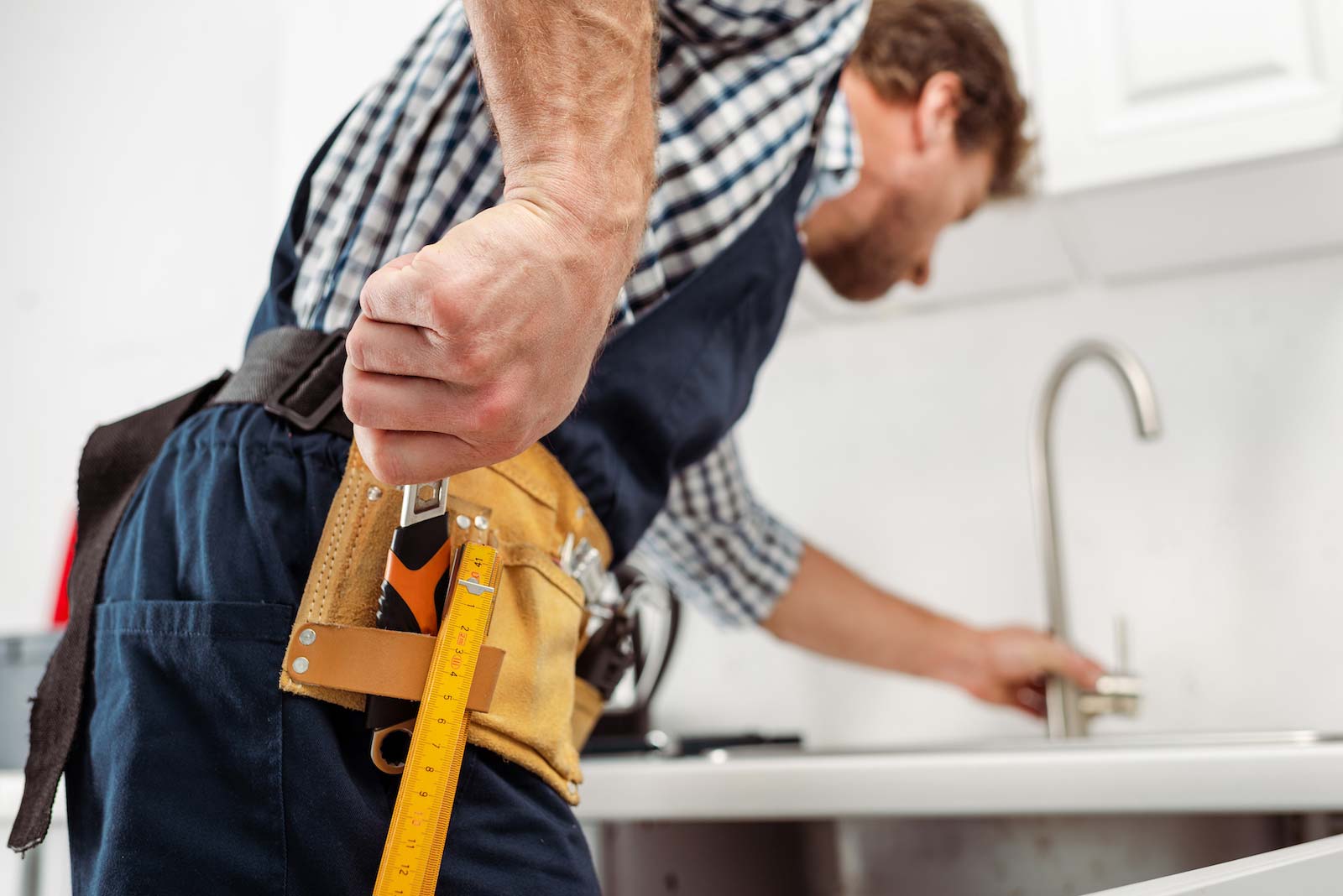 Workman reaches for tool on toolbelt
