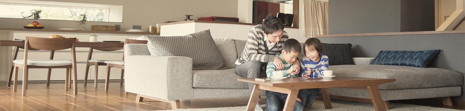 Dad teaching children how to us a tablet in living room