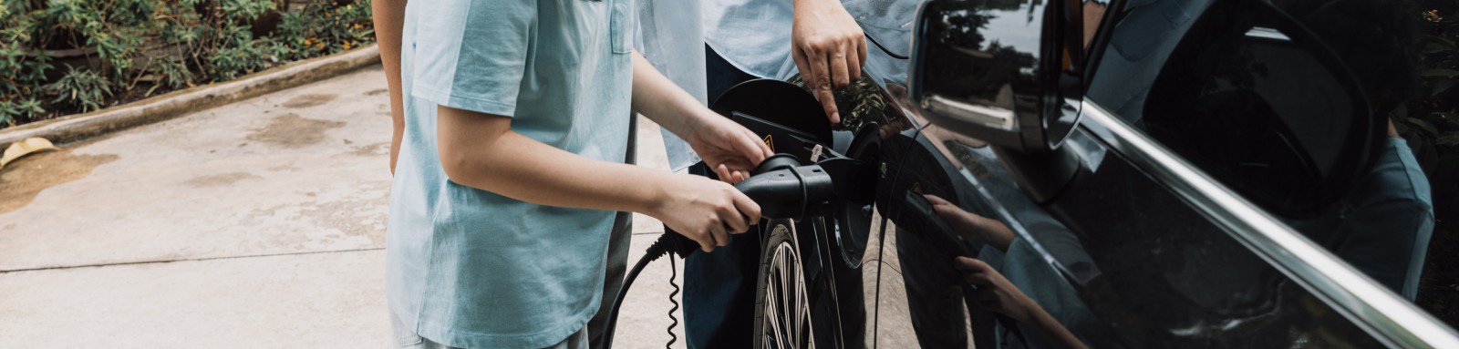 Child plugs in electric vehicle with fathers supervision