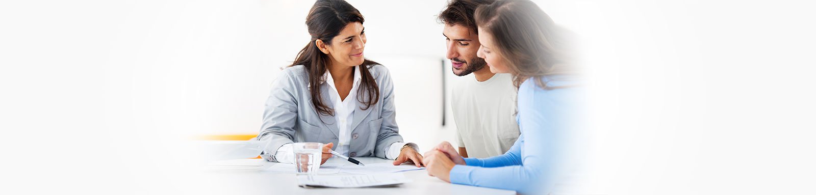 Couple at table speaking to woman with paperwork