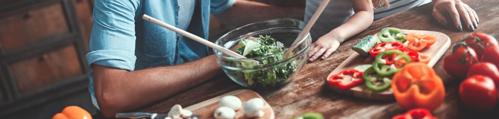 Angled wooden table cutting veggies for a salad