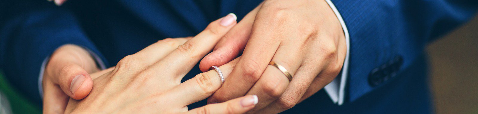 Groom putting an engagement ring on the finger of the bride