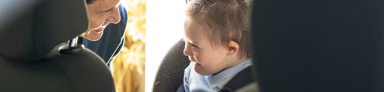 Man buckling boy into car seat