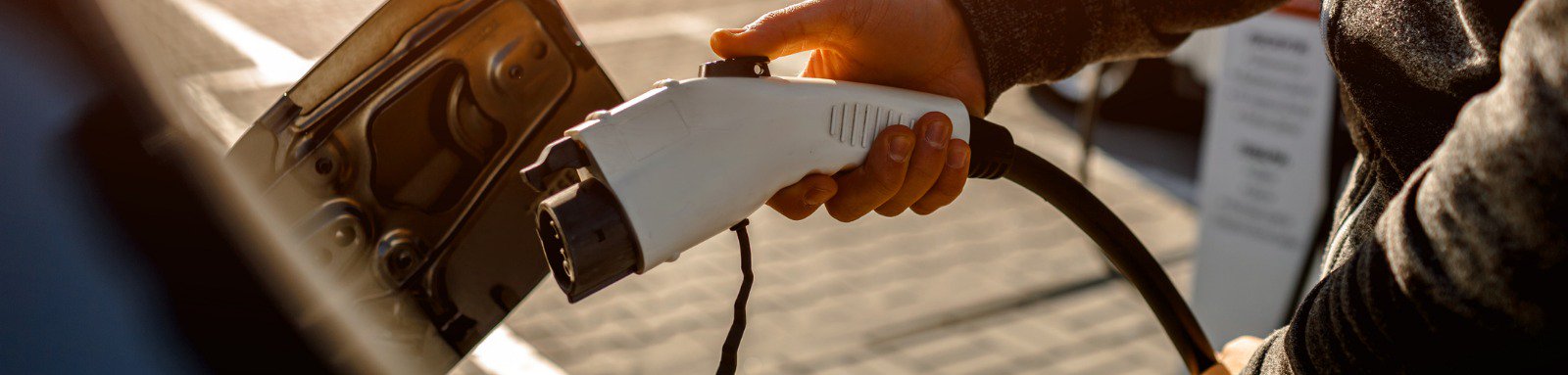 Man holding power charging cable for electric car