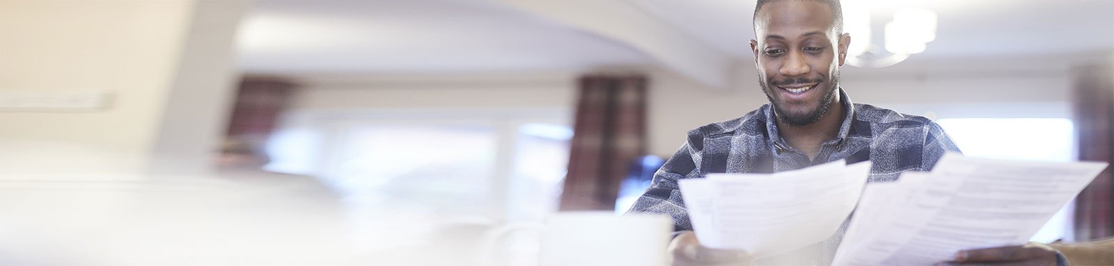 Man in checkered shirt looking at paper documents