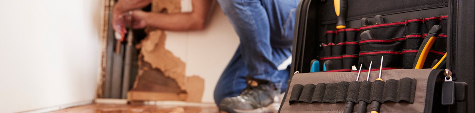 Middle aged man repairing burst pipe,plumbing, focus on foreground