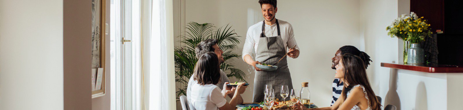 Man serving dinner to group at dining table