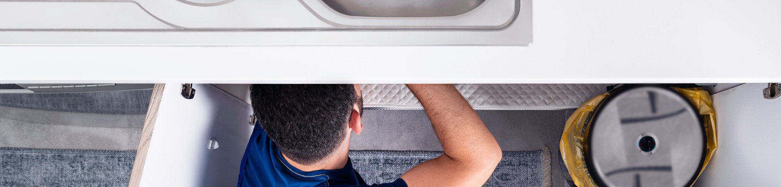 Man using tools under kitchen sink