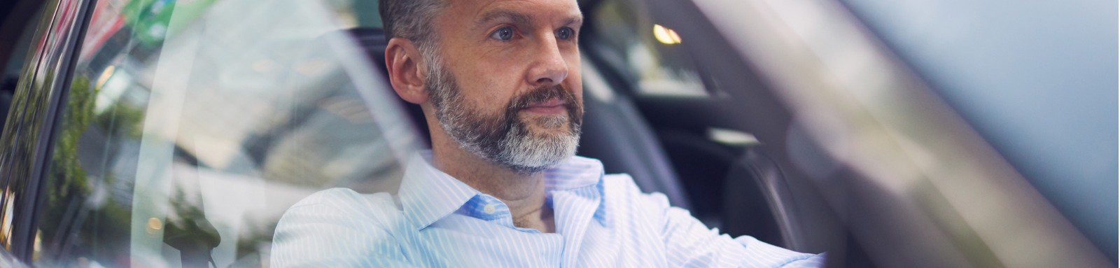 Mature man in pinstripe shirt driving car