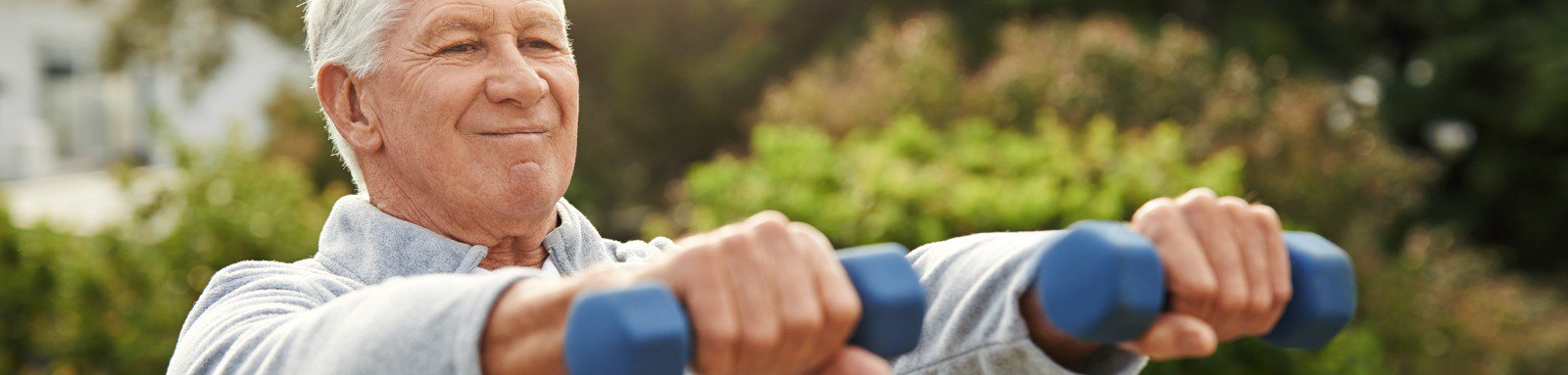 Older man holding weights outside