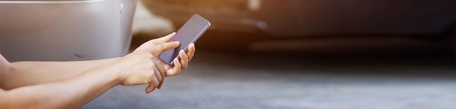 Person on smartphone next to crashed cars