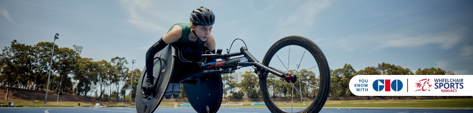 Smiling woman in wheelchair racing on racetrack