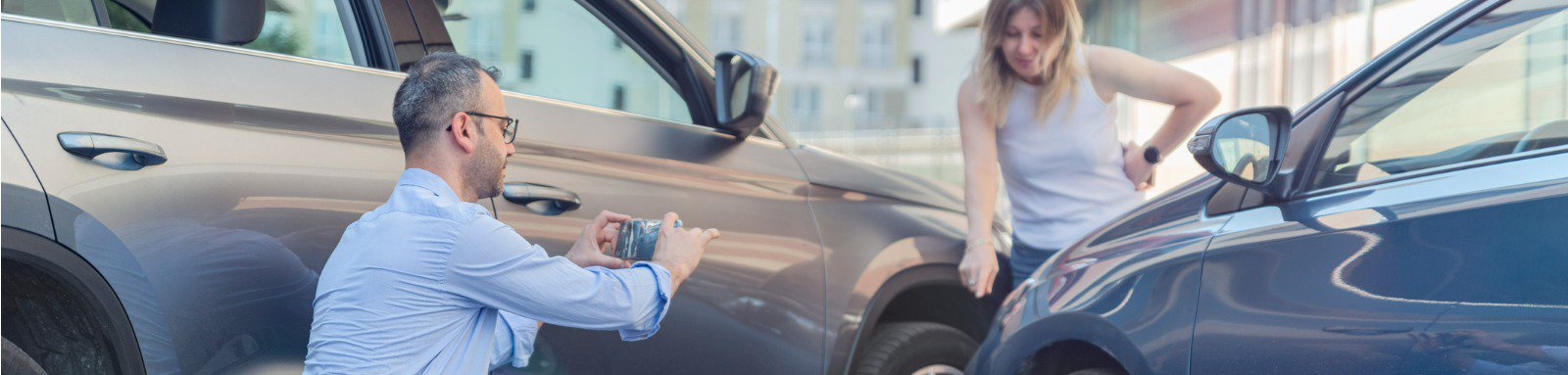 Two people photographing a car with a smartphone post accident