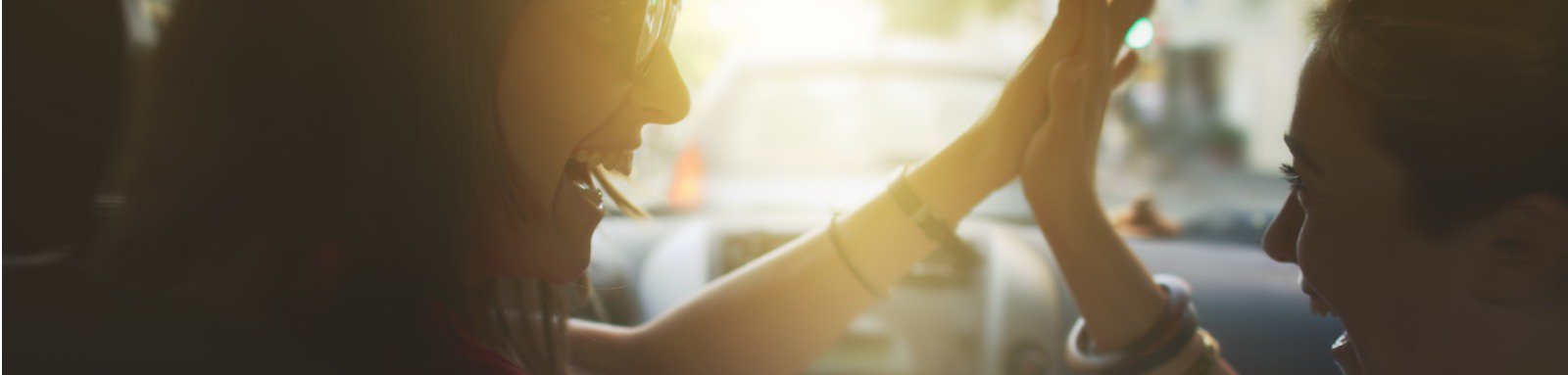 Two women high-fiving in a car