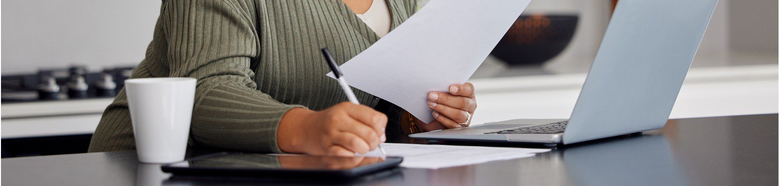 Woman doing some paperwork in front of laptop at home