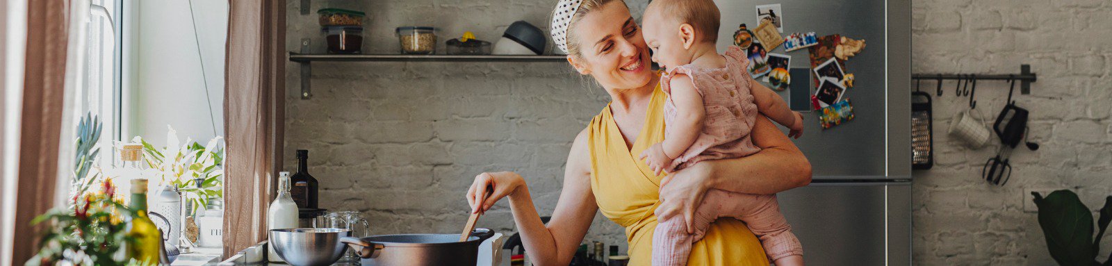 woman holding baby while she stirs a pot