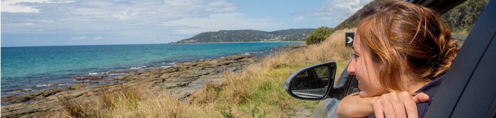 Woman looking out car window at coastline