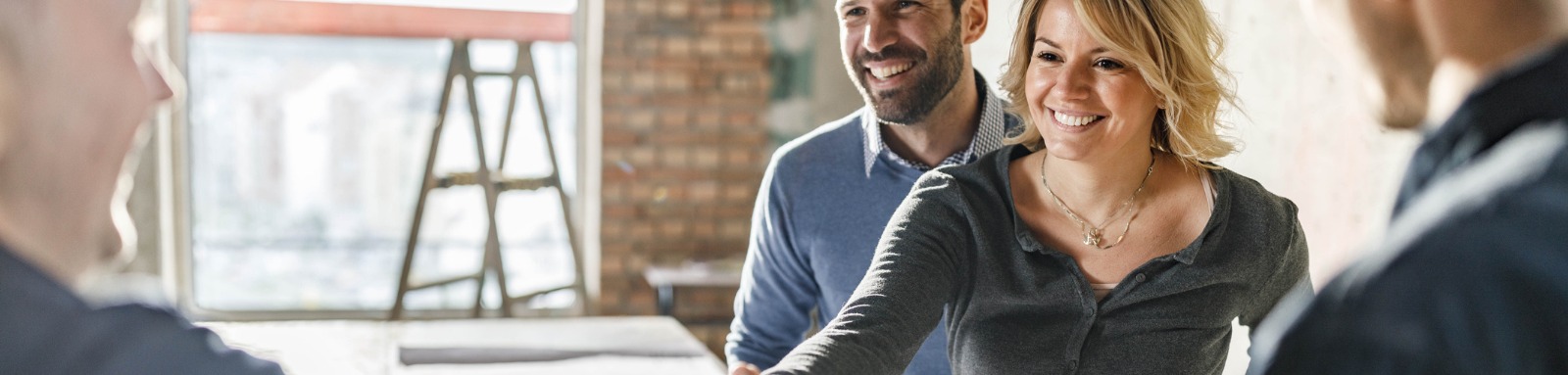 Woman shaking builders hand in unfinished home