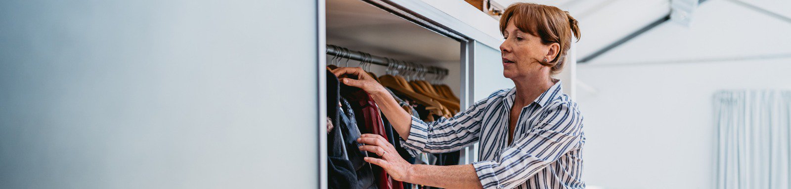 Woman taking clothes from wardrobe