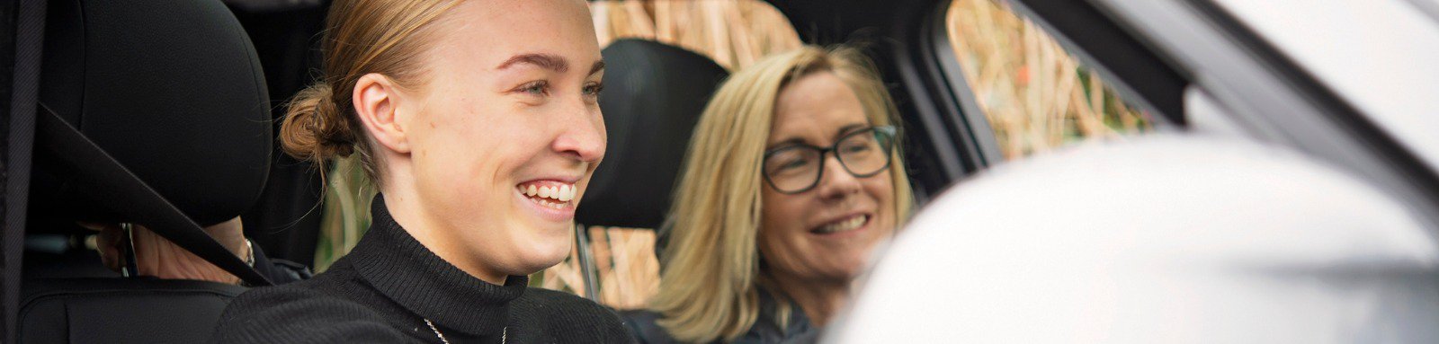 Young woman learning to drive with older woman