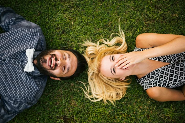 Ccouple lie on grass laughing