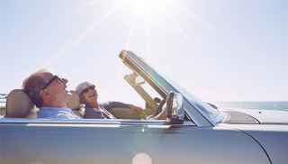 Senior couple happily driving a convertible