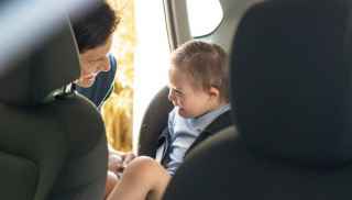 Man buckling boy into car seat