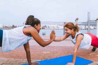 Two woman in push up position high fiving one another